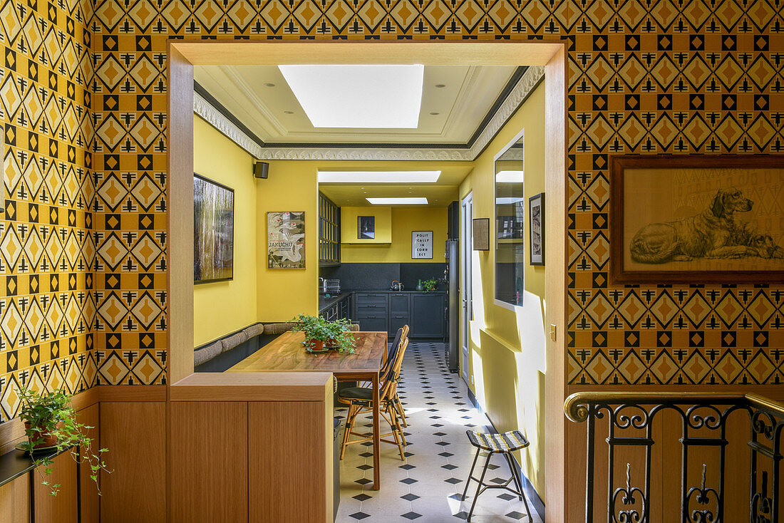 Patterned wallpaper around open doorway leading into dining room and open-plan kitchen