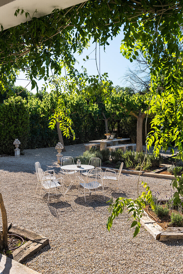 A sunny gravel area with a filigree table and chairs