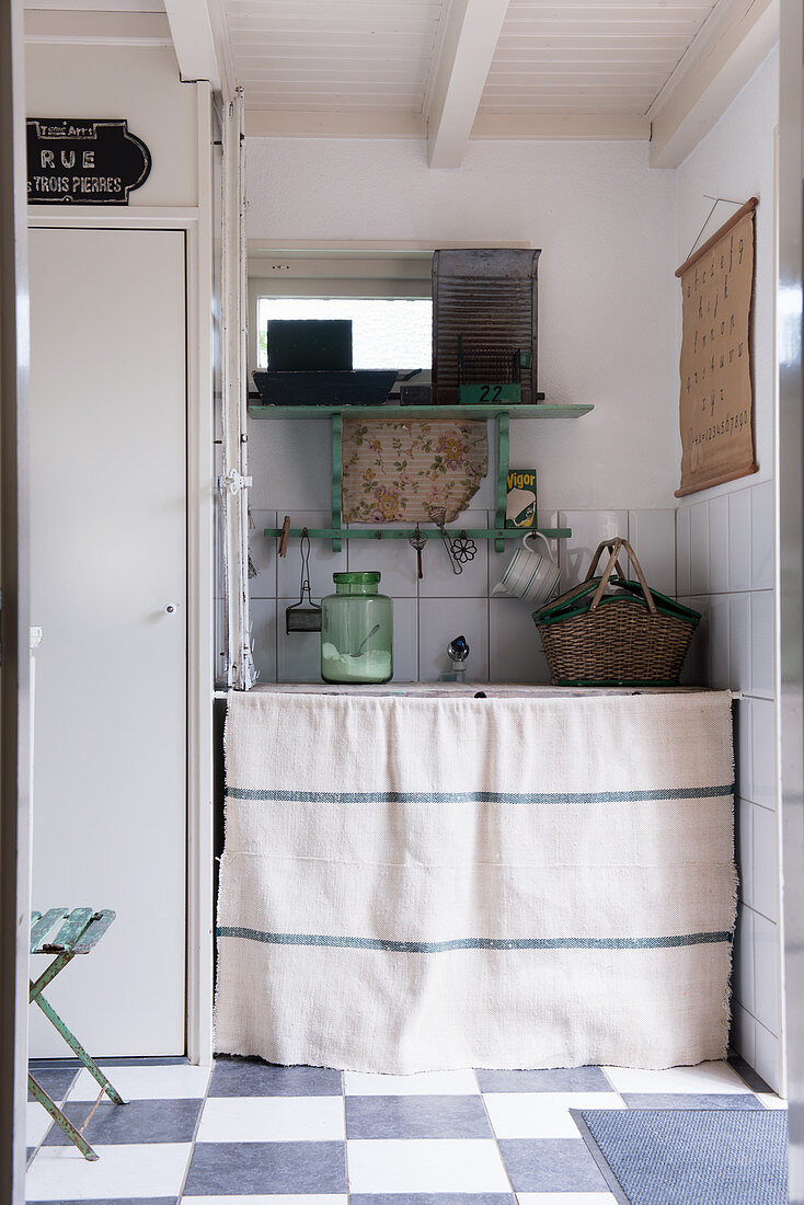 A laundry room with a washing machine behind a linen curtain