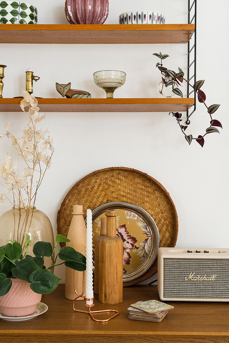 Vase, Holzflasche, Tablett und Vintage Radio, darüber Regal mit Dekoobjekten