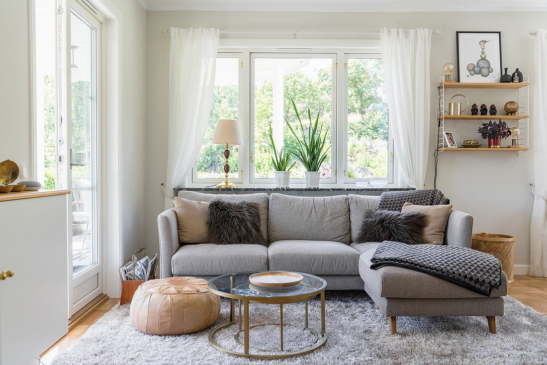 A grey upholstered sofa on a matching rug in a bright living room