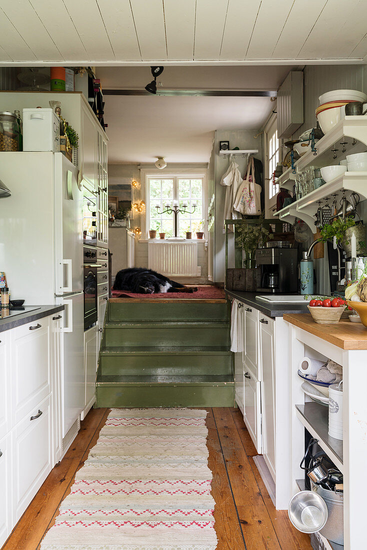 Holztreppe führt in die schmale Küche mit offenem Regal