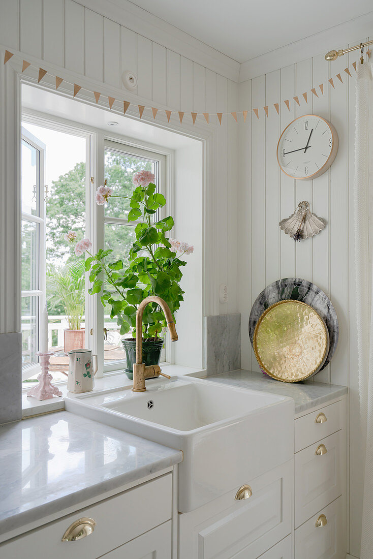Weiße Küchenzeile mit Spülbecken vor dem Fenster