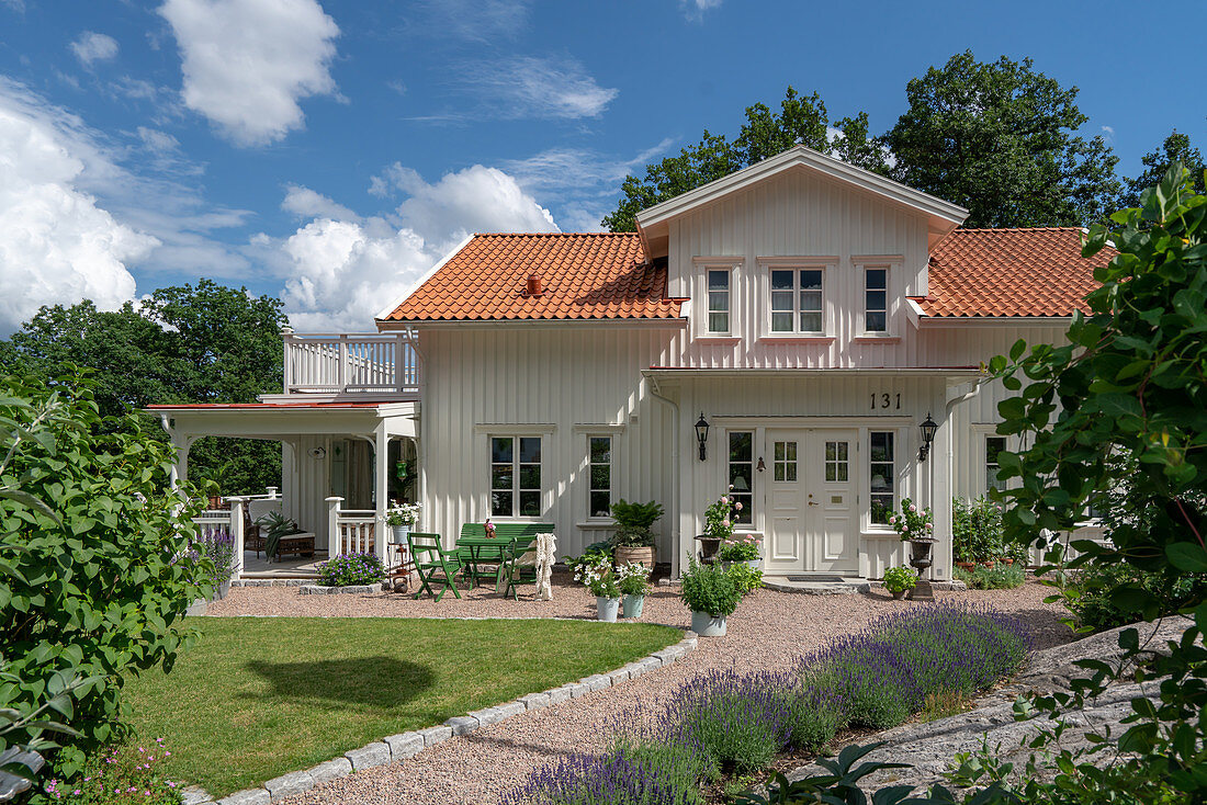 A white wooden house with a sunny garden
