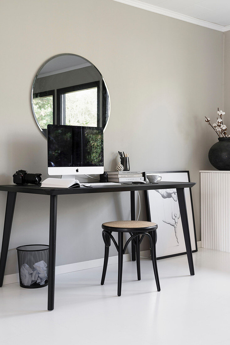 A home office on a kitchen table in front of a grey wall