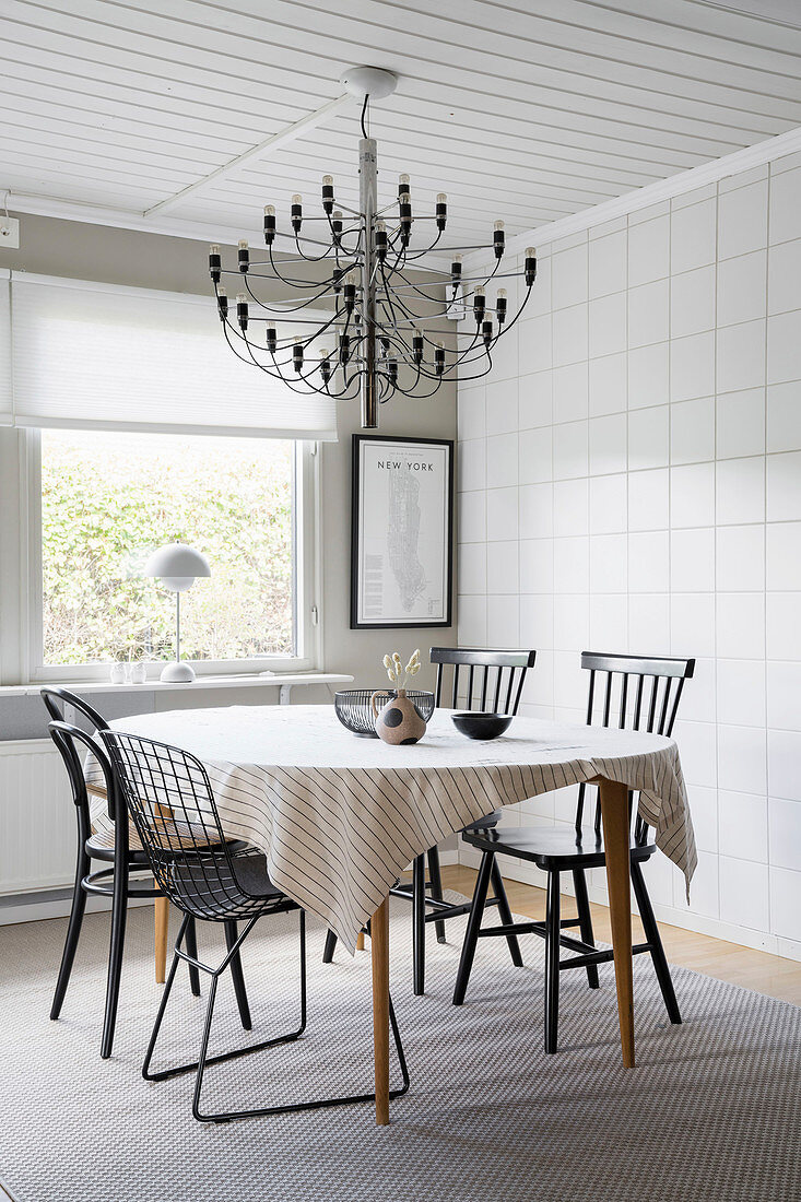 A dining area with various chairs and chandeliers in front of a tiled wall