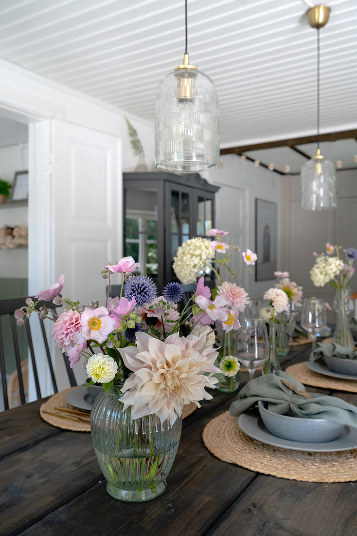 Flowers on a laid wooden table with lights with glass shades hanging above it