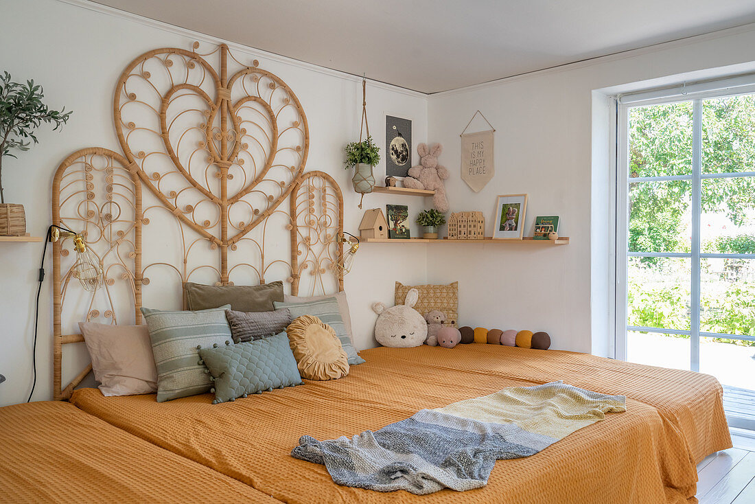 A bed with a rattan headboard in a cosy bedroom