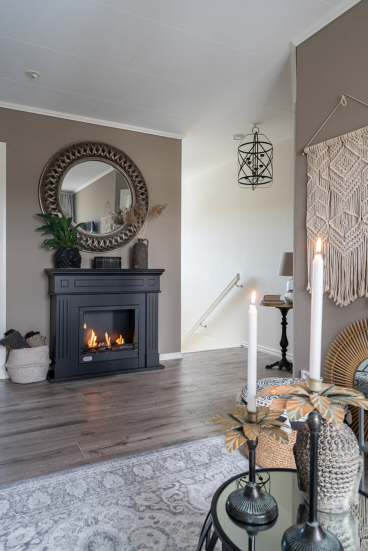 A round mirror on a taupe wall over a fireplace