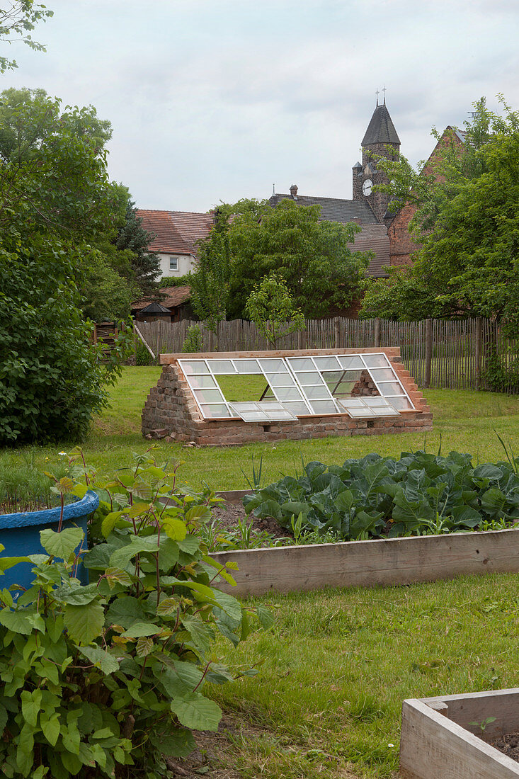 Vegetable beds with surrounds made from boards and cold frame made from old windows in country garden