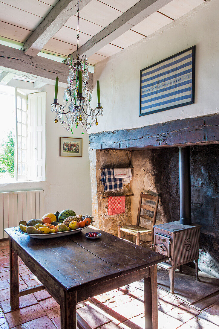 Kronleuchter über Holztisch in rustikaler Küche mit Holzofen