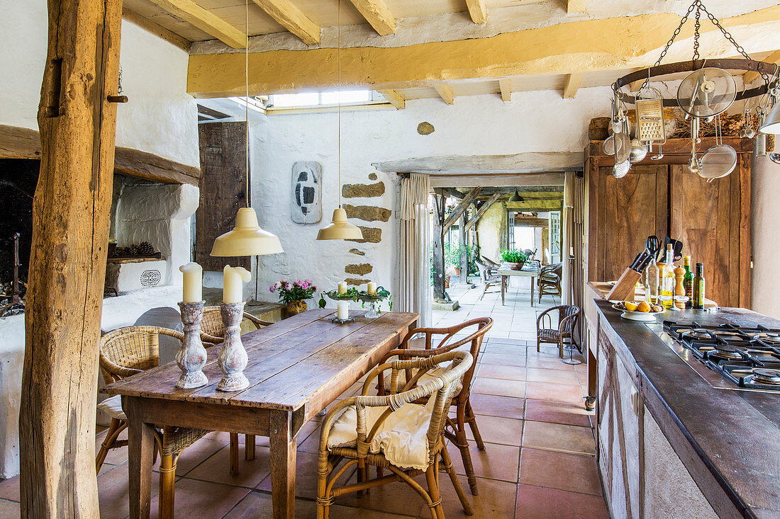 Wooden table with rattan chairs in country kitchen with wood-beamed ceiling