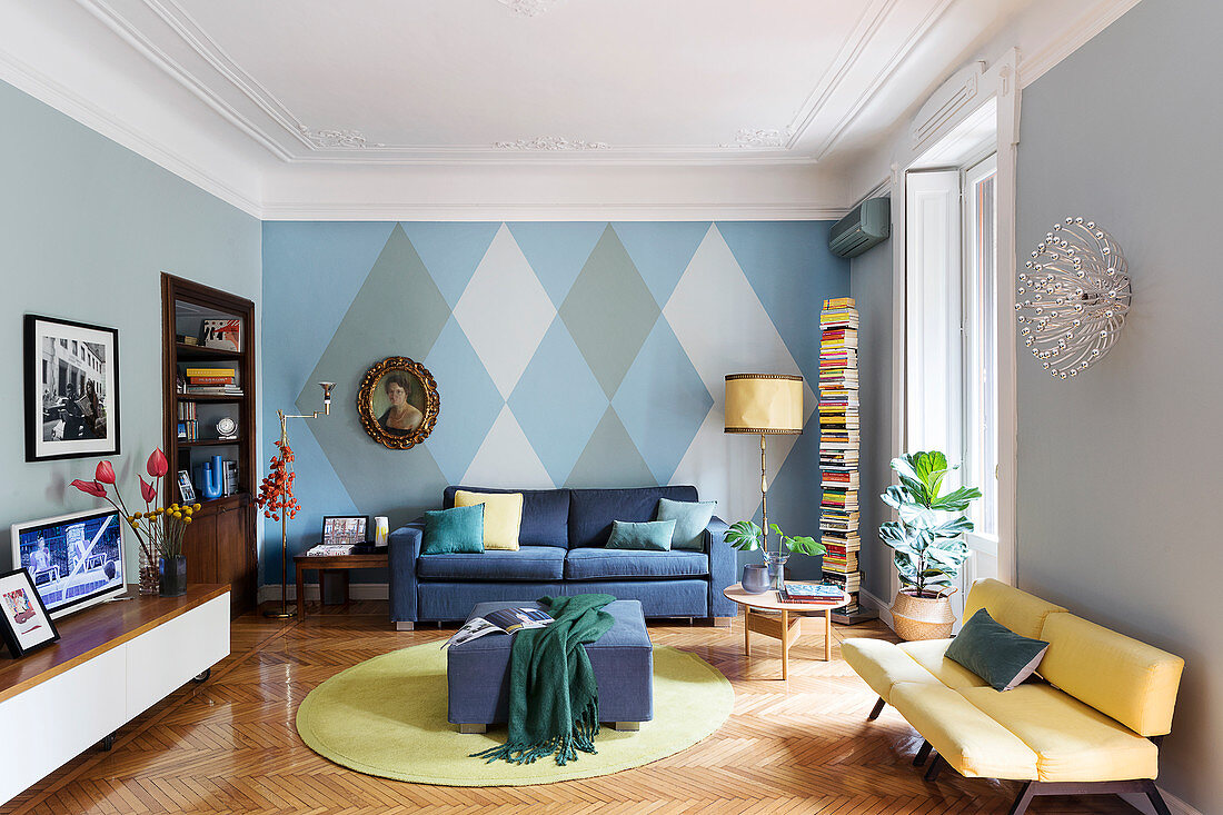 Seating furniture in a living room with a diamond-shaped wall pattern, stucco moulding and a parquet floor
