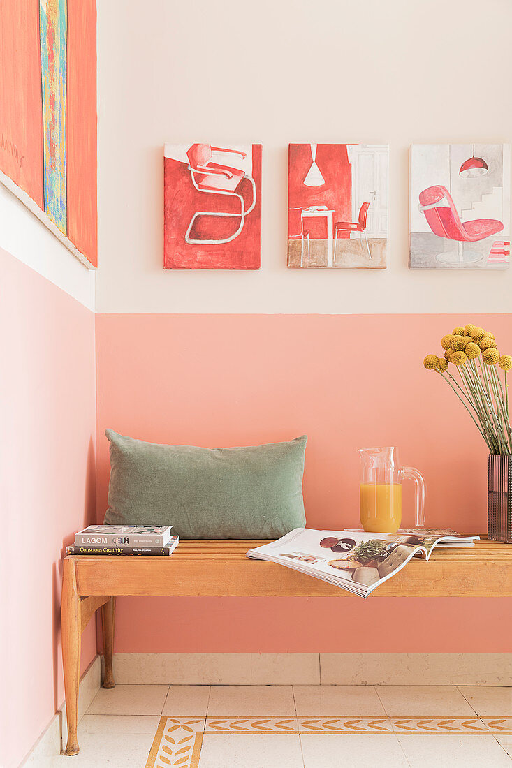 Holzbank mit Kissen vor rosafarbener Wand in der Küche