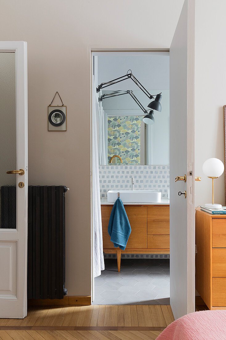 A view into a bathroom with a vanity unit and a wall lamp