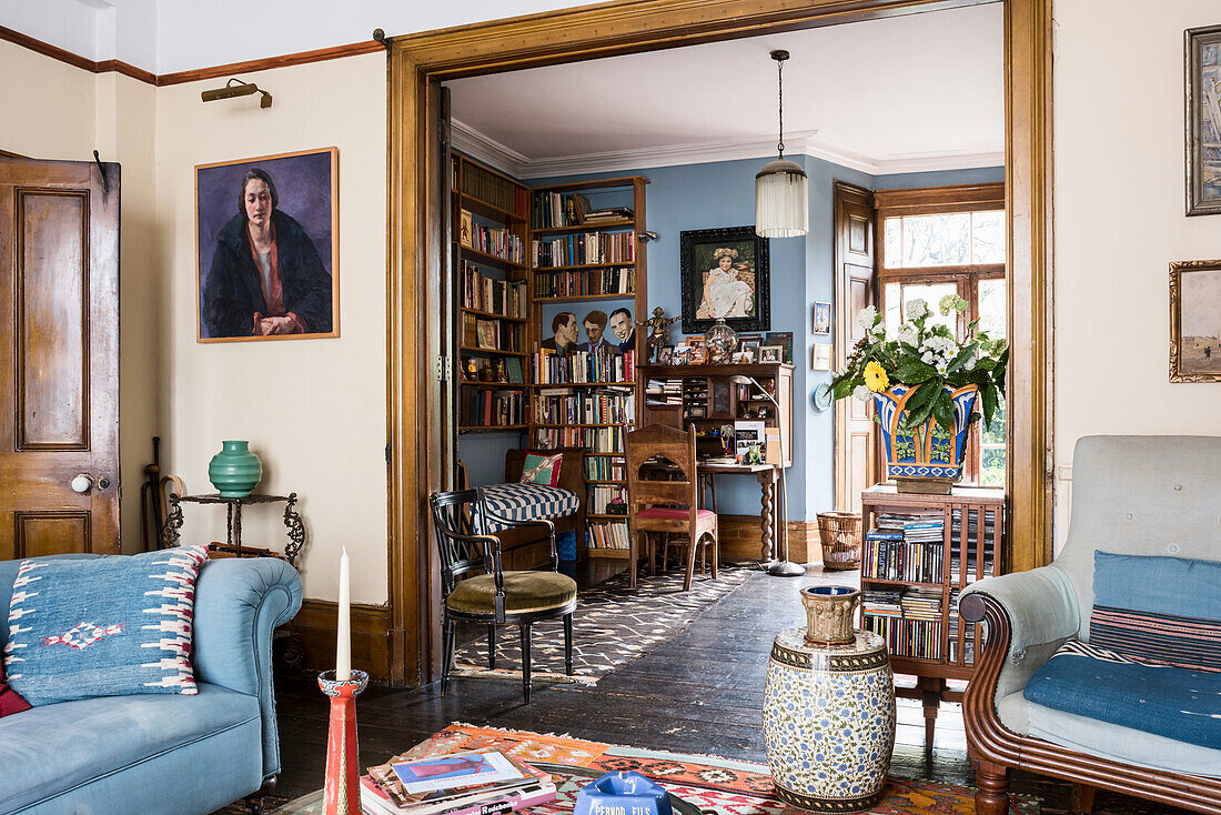 Salon mit blauem Sofa, Blick auf drehbares Bücherregal im Stil von Arts and Crafts im Arbeitszimmer