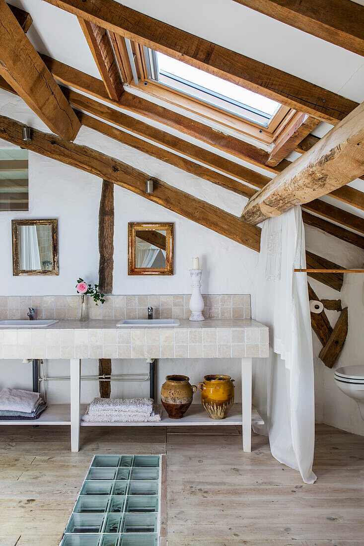 Double washstand in rustic attic room with wood-beamed ceiling