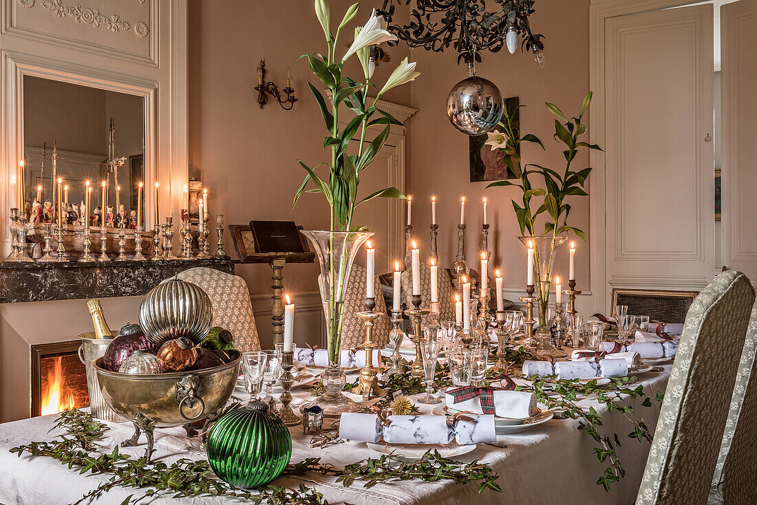 Festively laid Christmas table, above antique copper chandelier and mercury candlestick on mantelpiece