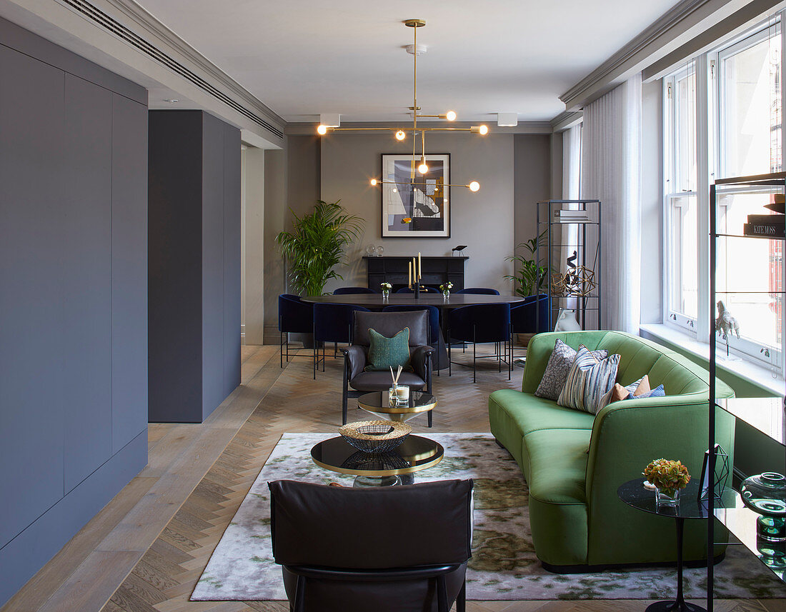 Green sofa, dining area and fitted cupboards in elegant interior