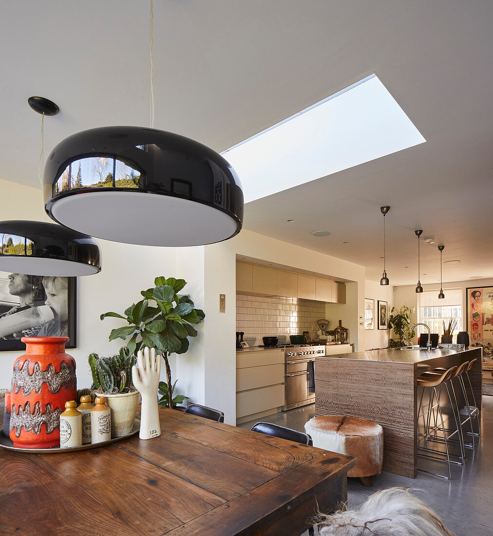 Schwarze Deckenlampen überm Esstisch vor der offenen Küche