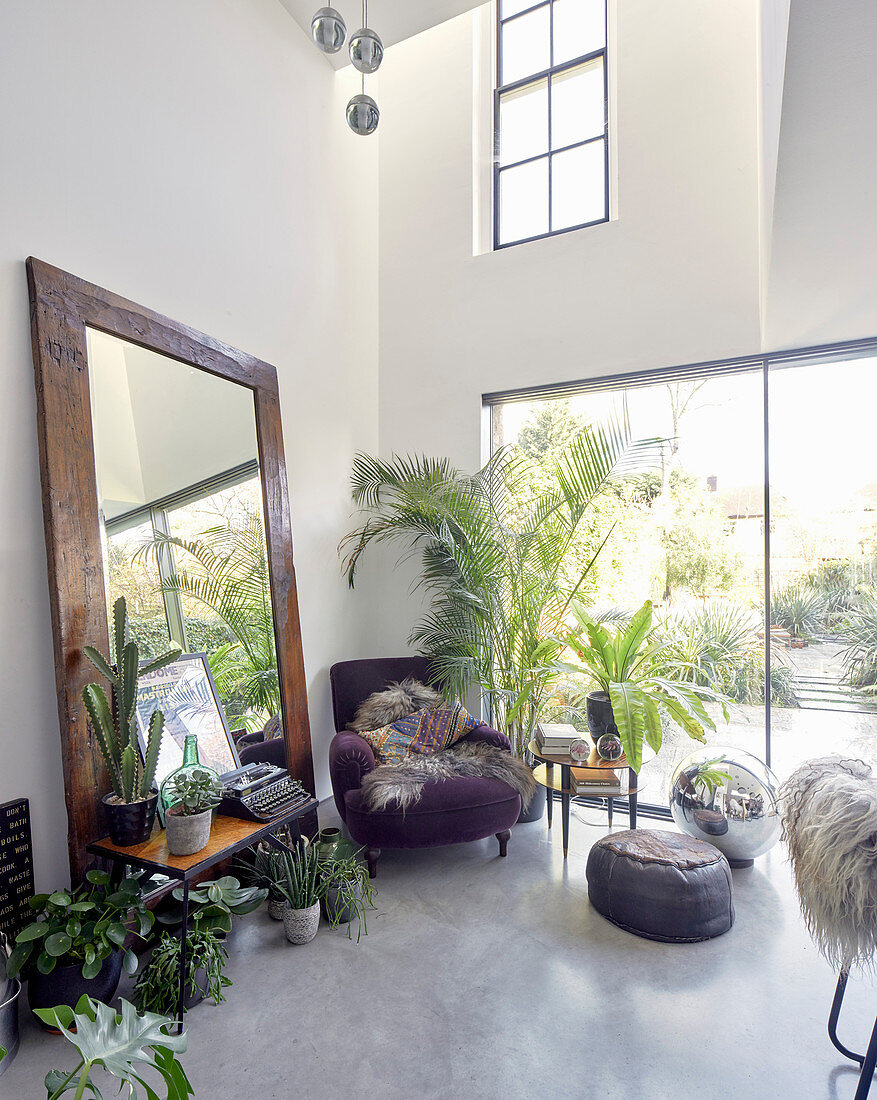 Floor-standing mirror and collection of houseplants in dining room with concrete floor