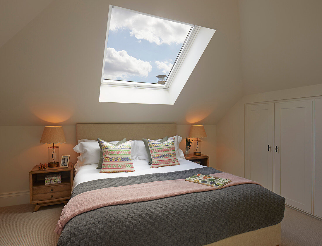 Bed below skylight with view of cloudy sky