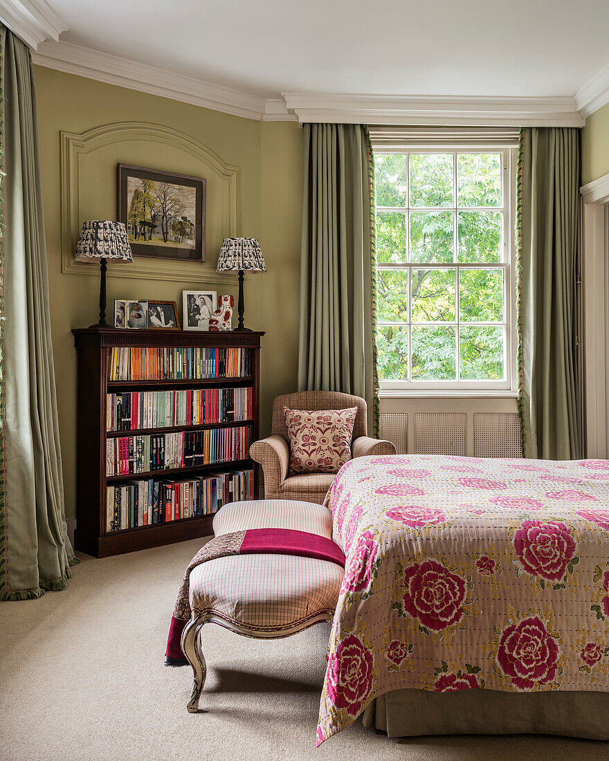 Tagesdecke mit Blumenmuster auf Bett und Vintage Bücherregal im viktorianischem Schlafzimmer