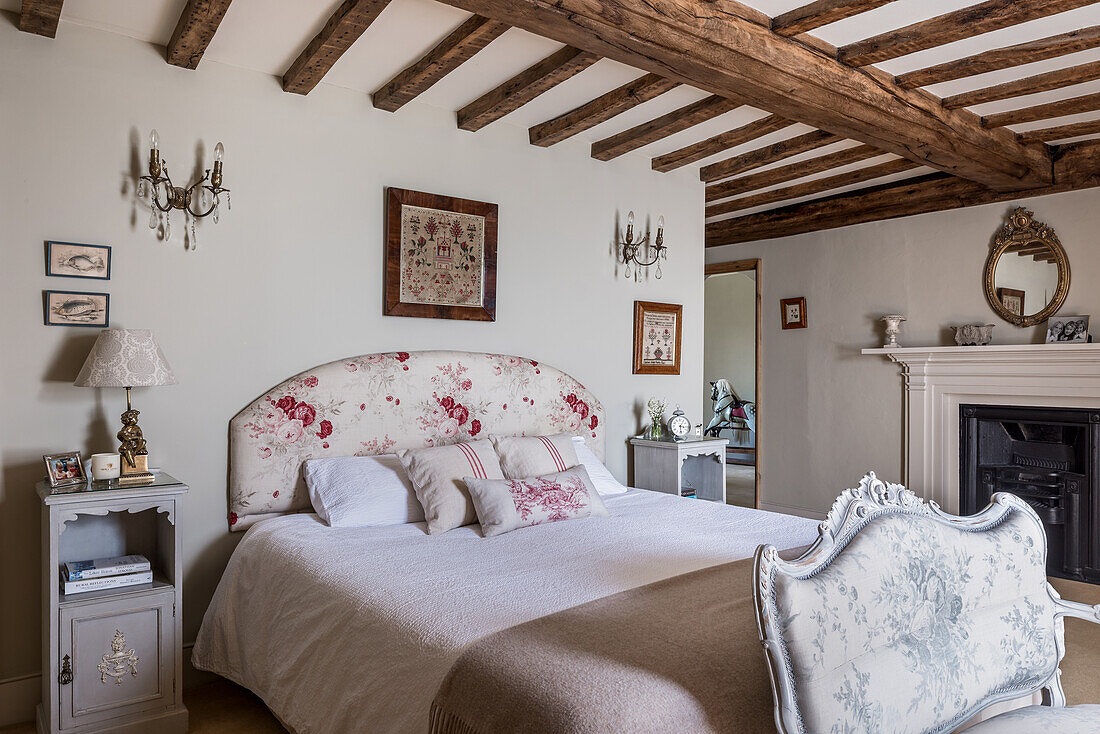 Emboidered folk art above double bed with floral headboard in 16th century farmhouse renovation