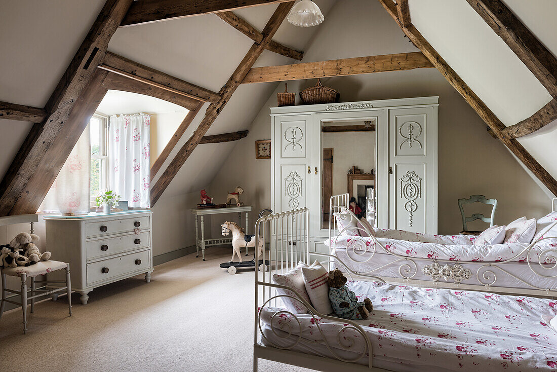 Twin beds and decorative wardrobe in roof space of restored 16th century farmhouse