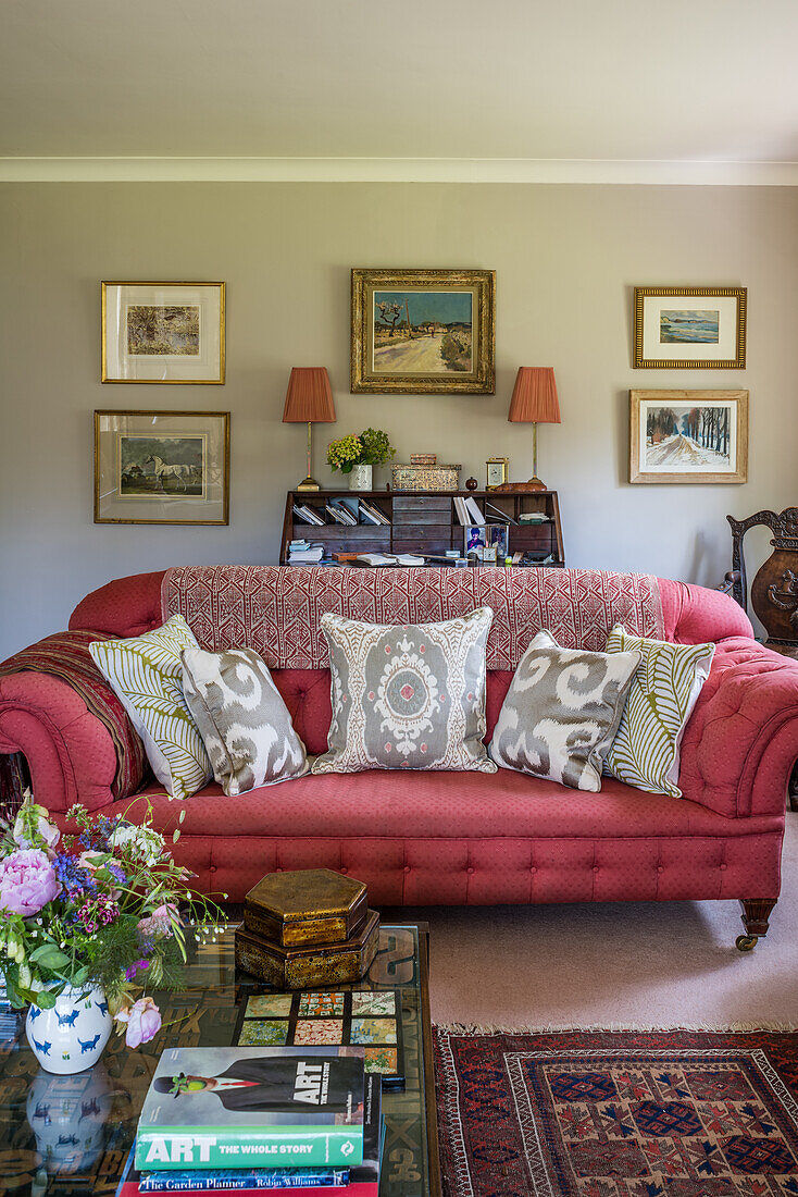 Grey cushions on pink Chesterfield with framed artwork