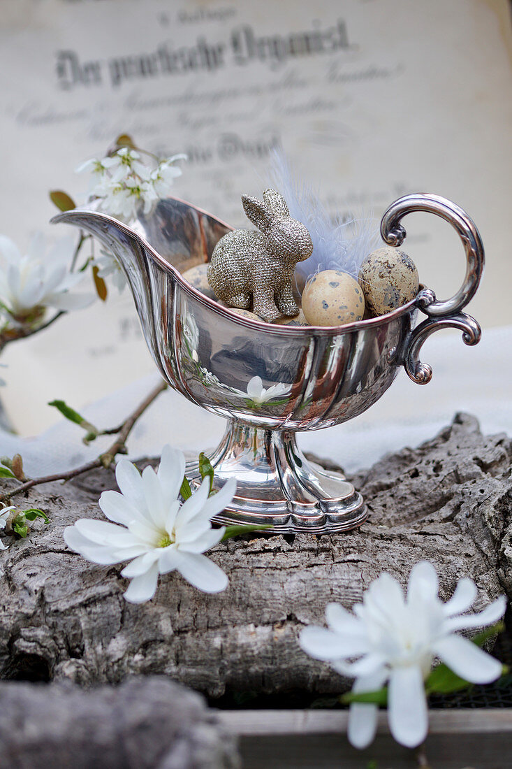 Silberne Sauciere mit Ostereiern und Osterhase, Blüten von Sternmagnolie und Felsenbirne