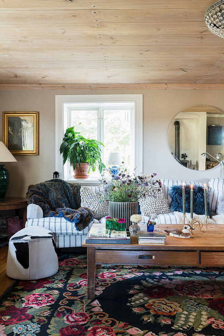 Cozy sofa with cushions, wooden coffee table and kilim rug in rural living room