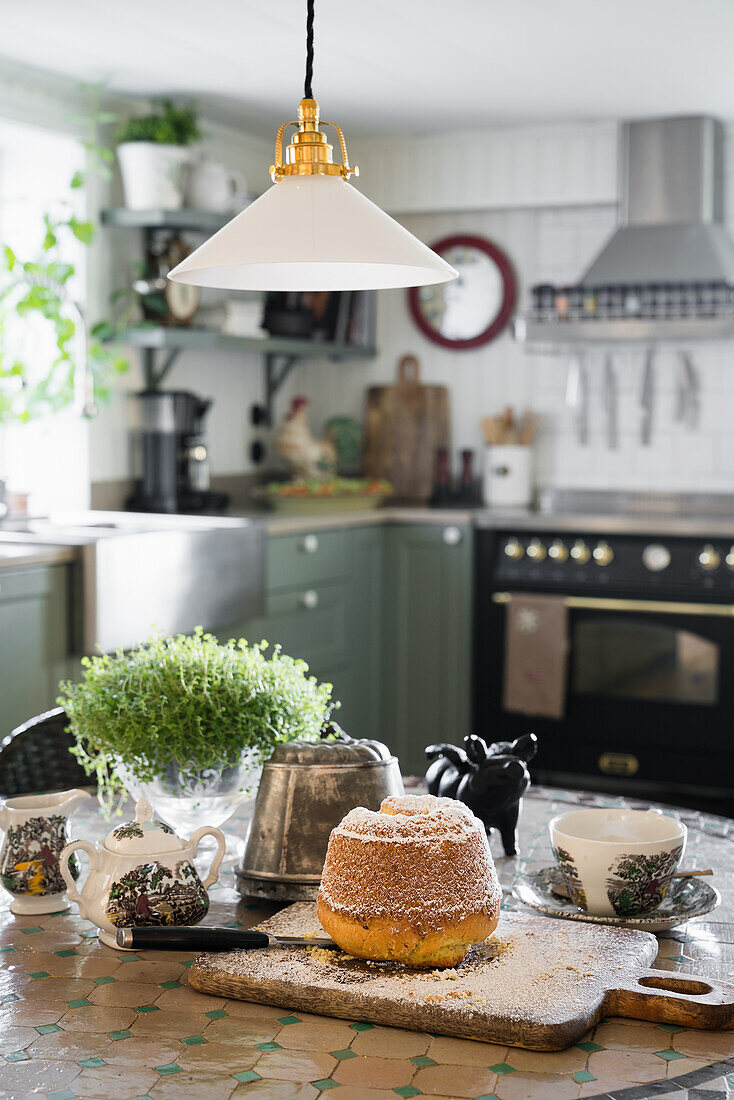 Kuchen und englisches Porzellan auf Küchentisch mit Mosaikplatte