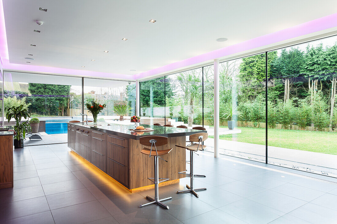 Elegante Kücheninsel mit indirekter Beleuchtung im Wohnraum mit rundum Verglasung