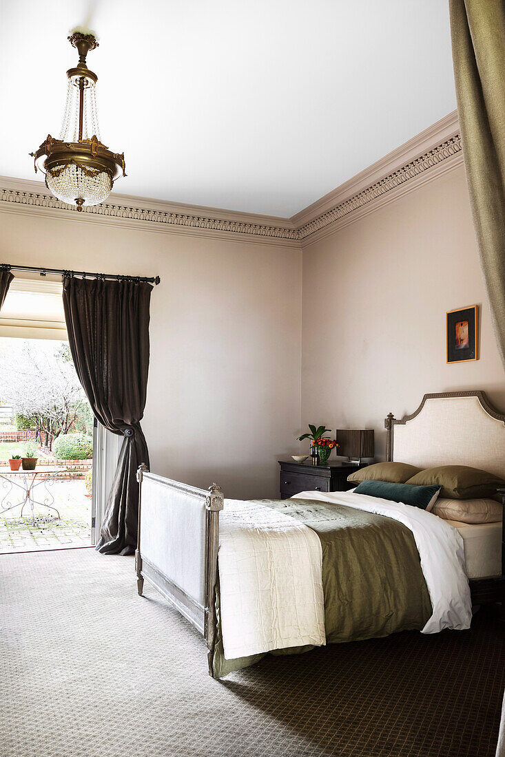 Antikes Doppelbett mit gepolstertem Kopf- und Fußteil im Schlafzimmer mit Terrassenzugang