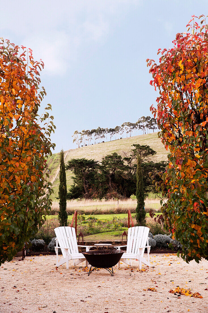 Feuerschale und zwei Stühle in herbstlichem Garten