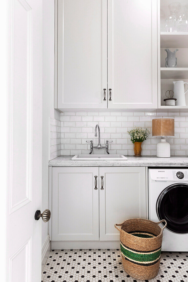 Laundry room with bright built-in cabinets and subway tiles