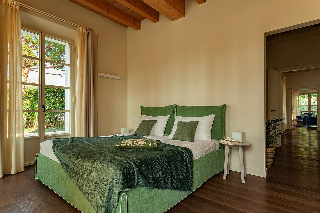 Doppelbett mit grünem Bezug und grüner Tagesdecke