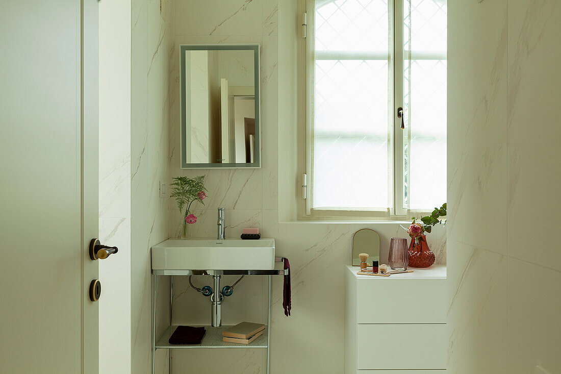 A bright bathroom with a chrome washstand and a dresser