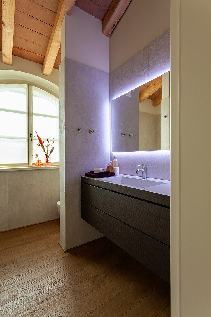 An ensuite bathroom with a washbasin and an illuminated mirror