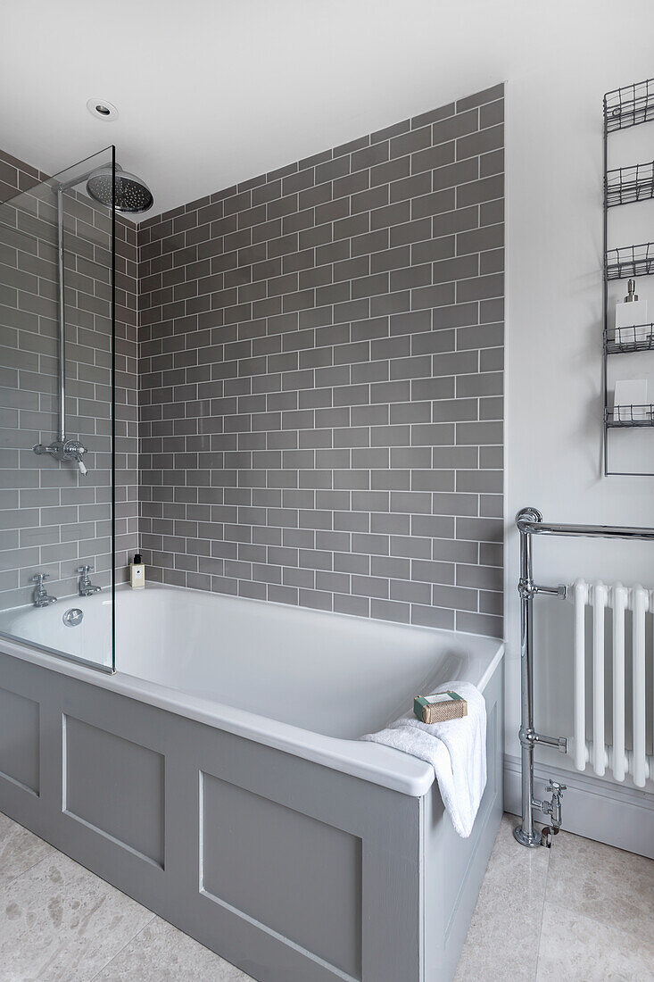 Bathtub in bathroom with grey wall tiles