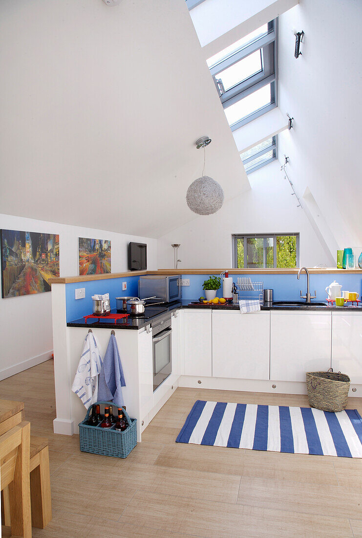 Blaue Rückwand in moderner, weißer Küche mit blau-weiß gestreiftem Teppich