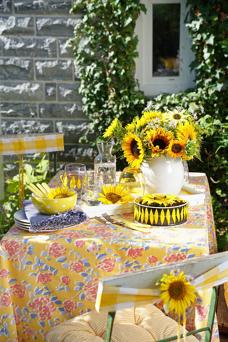 Gedeckter Tisch mit Sonnenblumenstrauß im Freien