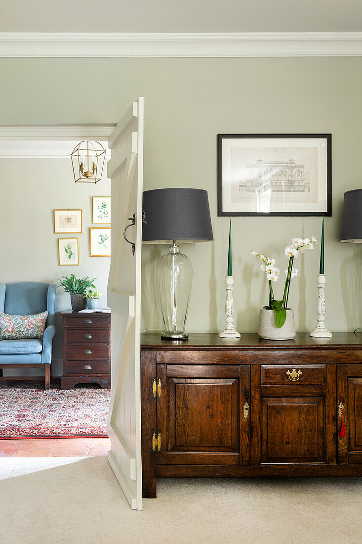 Glass lamps with black shades, candlestick, and orchid on an antique sideboard