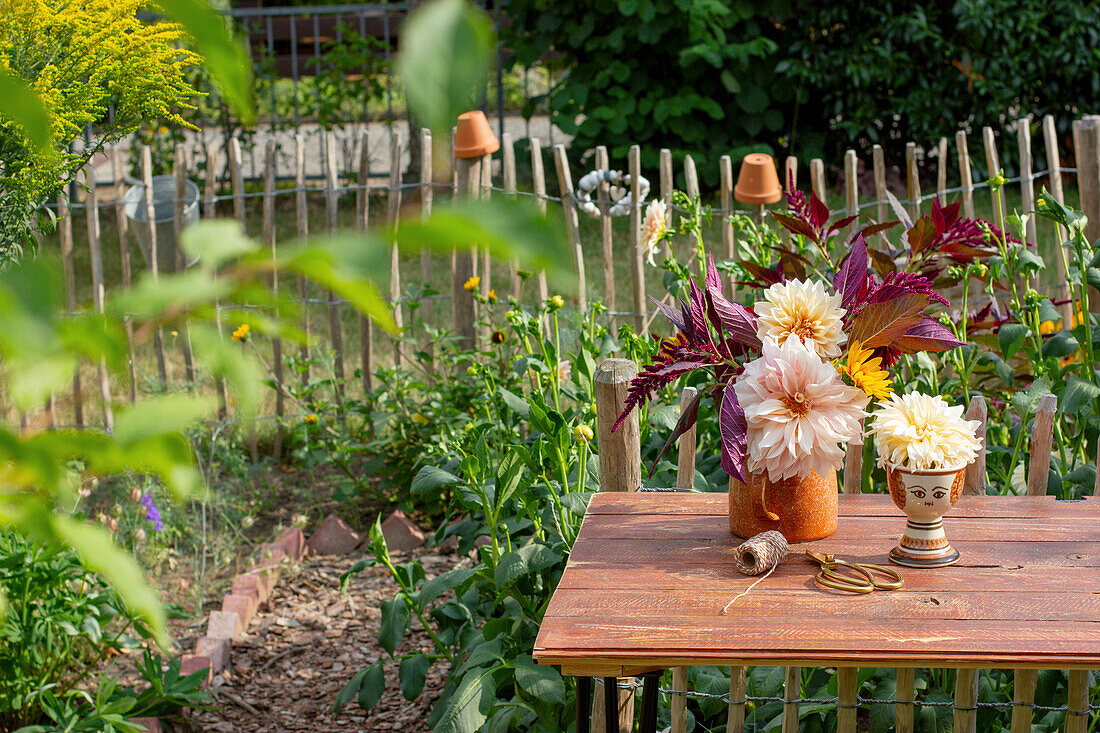 Dahlienblüten in Vasen auf Gartentisch