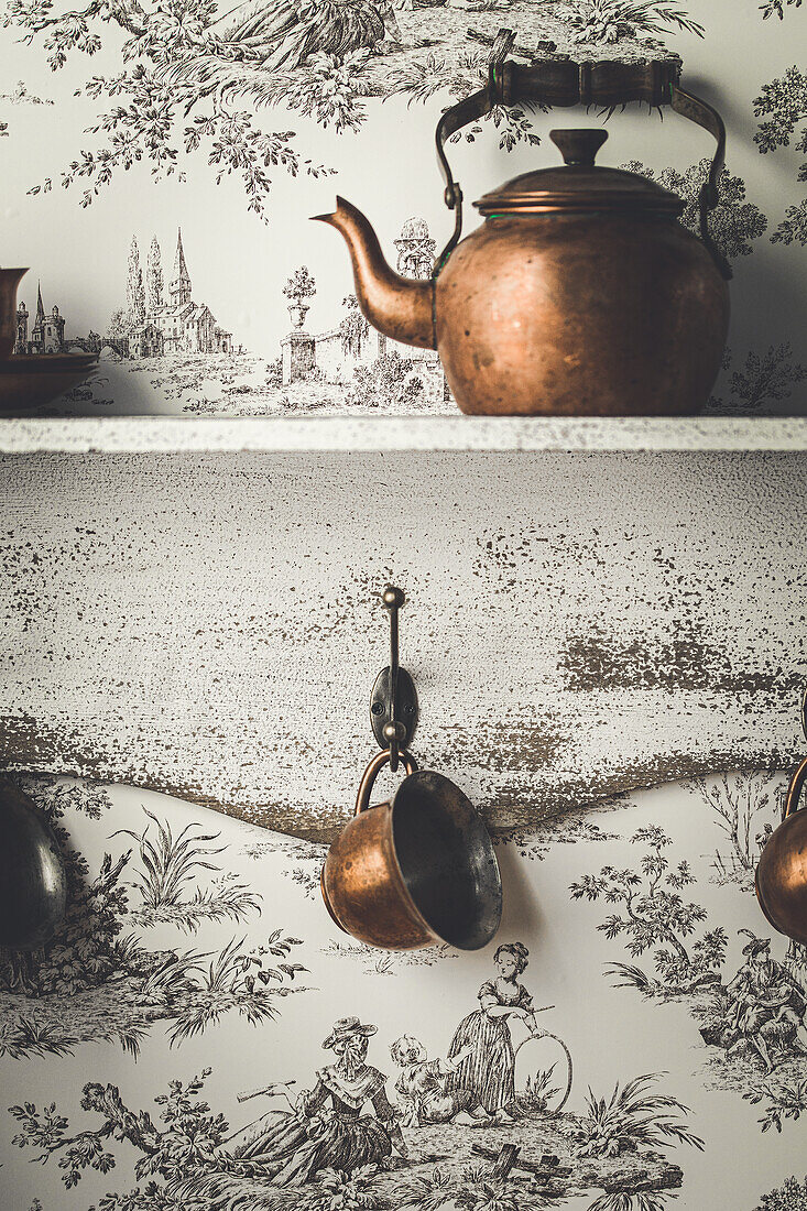 Kettle and tea cups in front of Toile de jouy wallpaper