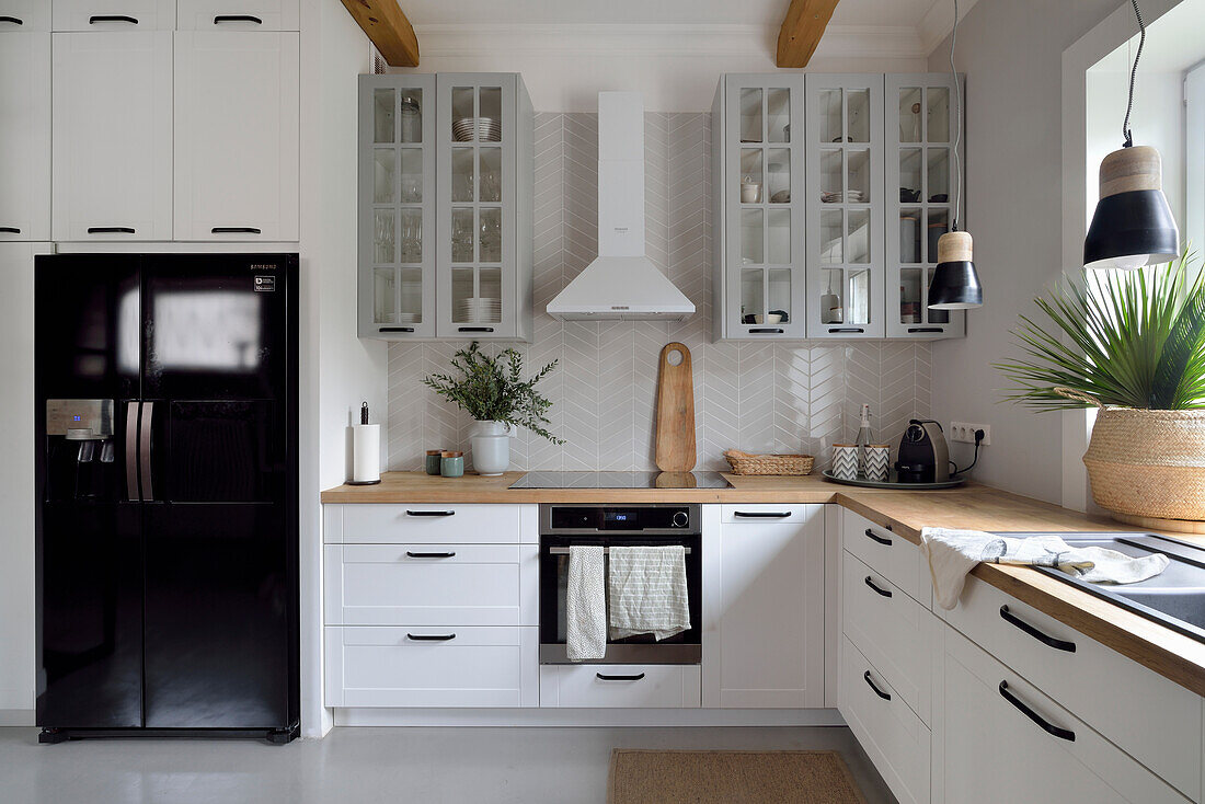 Weiße Küche mit Holzarbeitsplatte und schwarzem Side-by-Side Kühlschrank