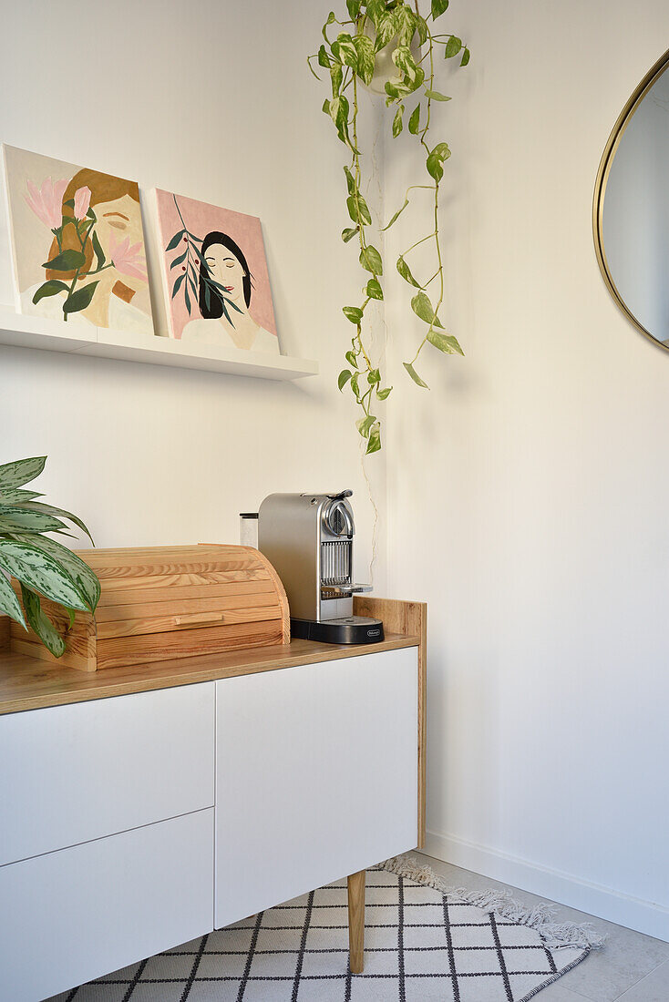 Lowboard mit Brotkasten und Küchenmaschine, darüber Regal mit moderner Kunst und Zimmerpflanze