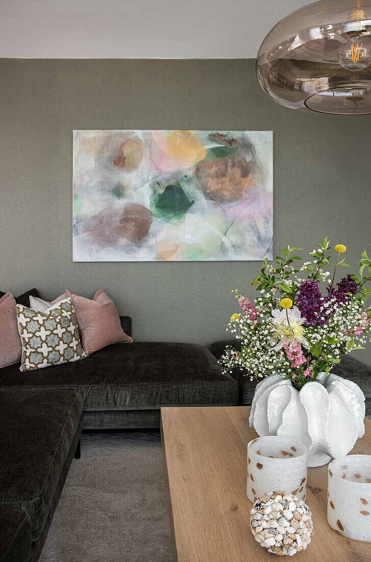 Large-format painting above ottoman and coffee table with bouquet of flowers in the living room