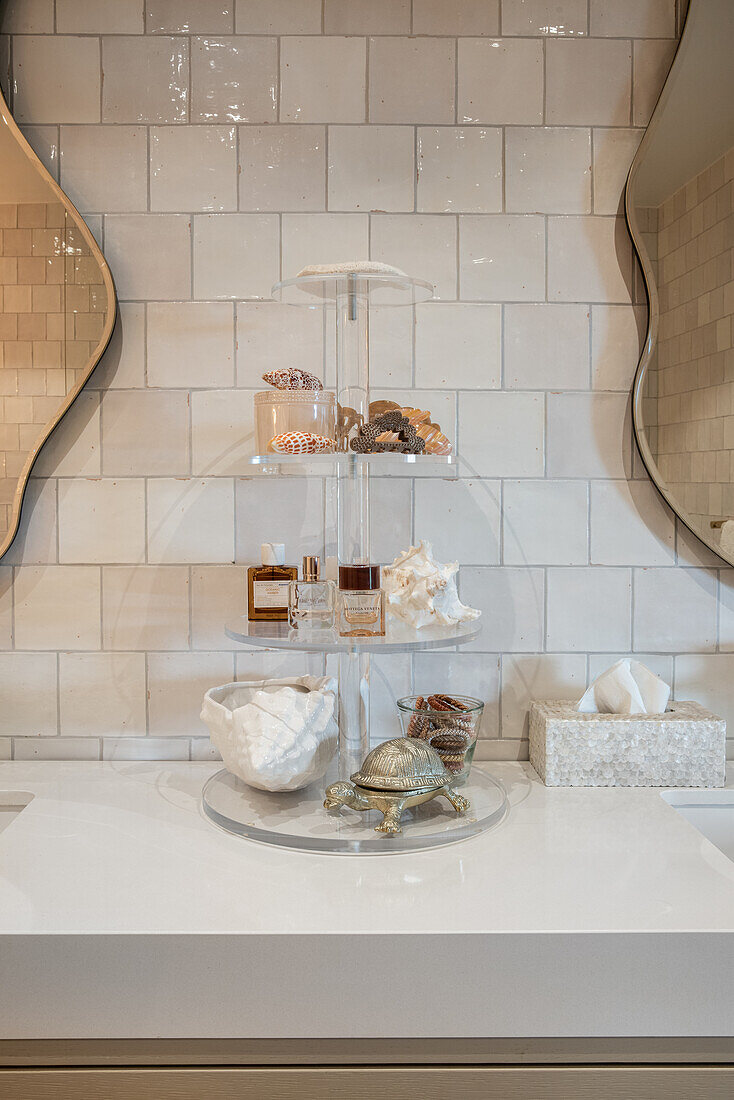 Round tiered glass shelf with perfumes and decoration in the bathroom